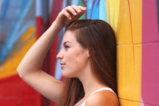 Side view portrait of a woman with colorful wall in the background.