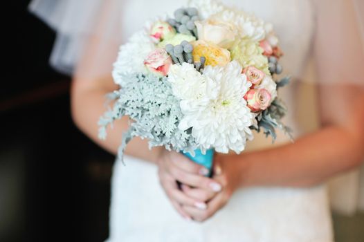 Wedding bouquet of white roses in bride's hands 