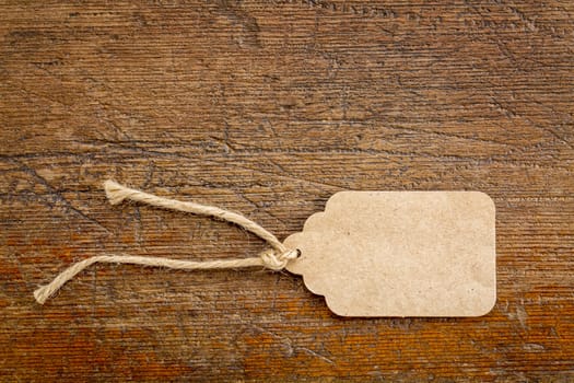 blank paper price tag with a twine against a rustic wood