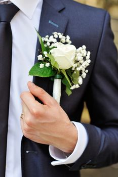 white rose boutonniere on suit of the groom