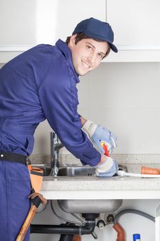 Happy man repairing de sink