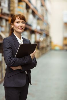 Portrait of pretty manager holding folder in a large warehouse