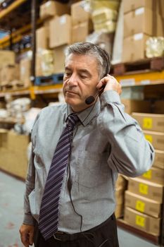 Focused manager talking in a headset in a large warehouse