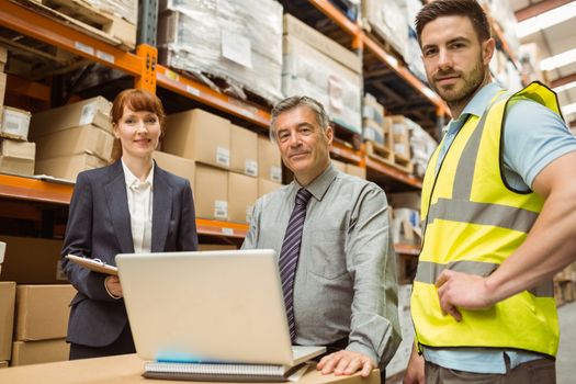 Smiling warehouse team looking at camera in a large warehouse