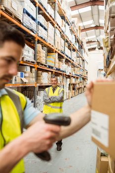 Warehouse worker scanning barcode on box in a large warehouse