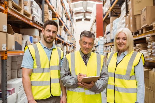 Warehouse team smiling at camera in a large warehouse