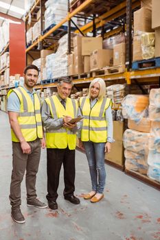 Warehouse team working together wile smiling at camera in a large warehouse