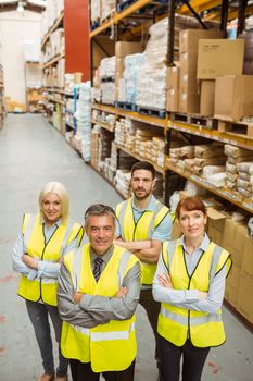 Smiling warehouse team with arms crossed in a large warehouse