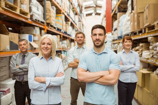 Smiling warehouse team with arms crossed in a large warehouse