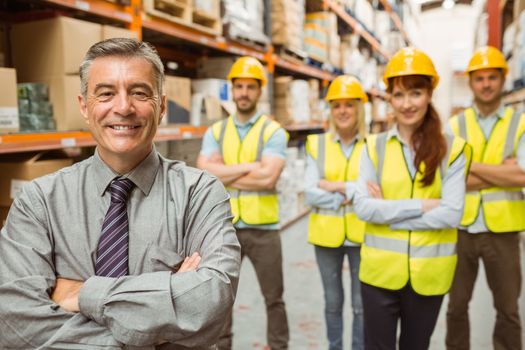 Smiling warehouse team with arms crossed in a large warehouse