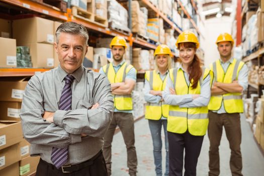 Smiling warehouse team with arms crossed in a large warehouse