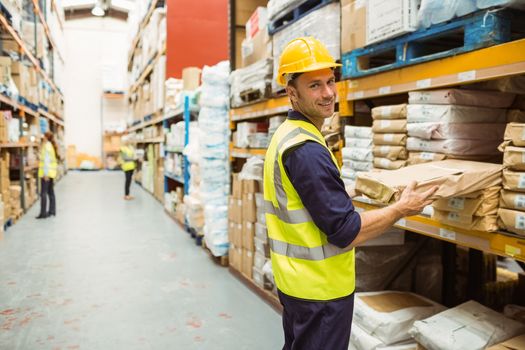 Warehouse worker taking package in the shelf in a large warehouse