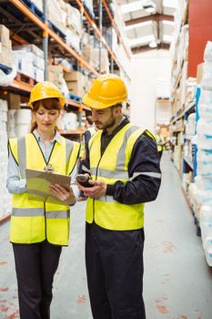 Warehouse manager talking with worker in a large warehouse