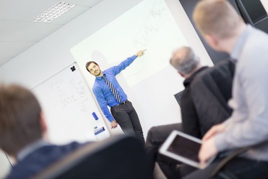 Business man making a presentation at office. Business executive delivering a presentation to his colleagues during meeting or in-house business training, explaining business plans to his employees.