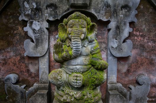 Sculpture of Ganesha covered with mold and moss. Traditional Hindu culture. Divine spirituality and total humidity are on Ganesha face.
