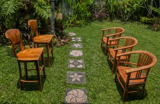 Wooden chairs assembled in the green garden. Environmental conversations and meetings. Informal communications.