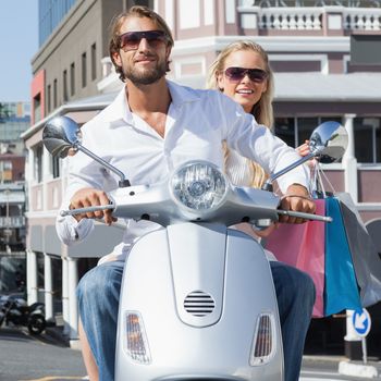 Cute couple riding a scooter on a sunny day in the city