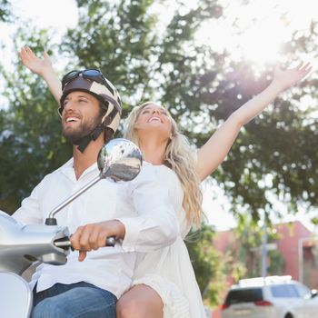 Cute couple riding a scooter on a sunny day in the city