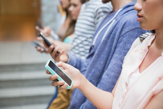 Students using their smartphones in a row at the university