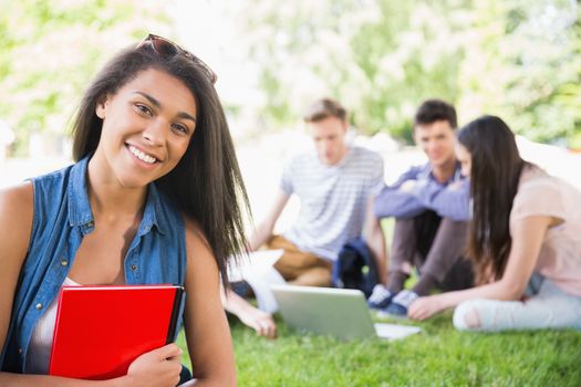 Happy students sitting outside on campus  at the university