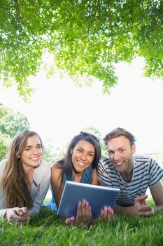 Happy students using tablet pc outside at the university