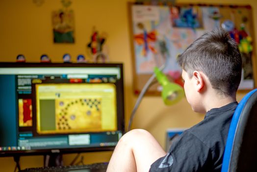 Teenager using computer at home with headphones, play game in his child room