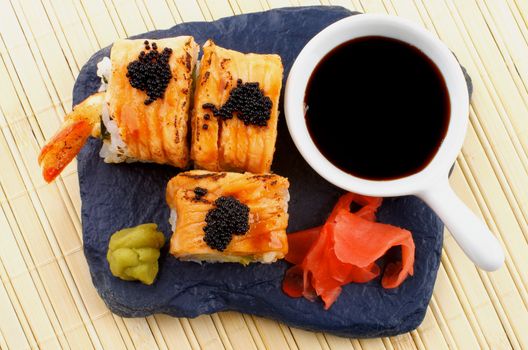 Arrangement of Maki Sushi with Salmon, Crab, Shrimp and Black Caviar on with Soy Sauce, Ginger and Wasabi on Black Stone Plate. Top View