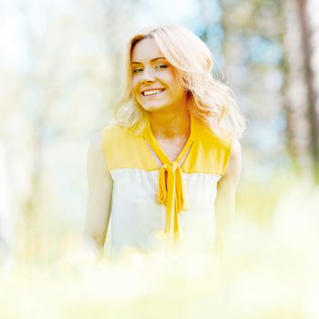 Beautiful young blond woman sitting on grass in park