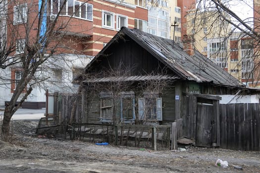 Old wooden houses against modern high-rise buildings. Tyumen, Russia