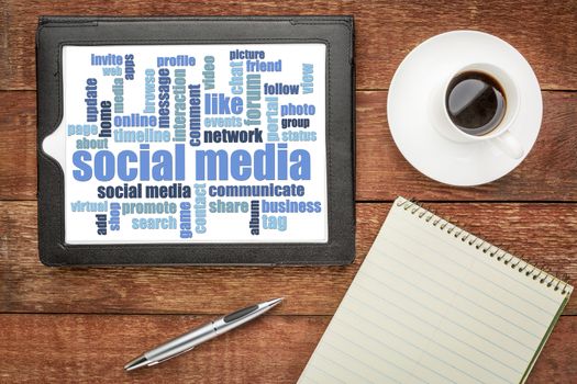 social media word cloud on digital tablet - top view on a rustic barn table with coffee and notepad