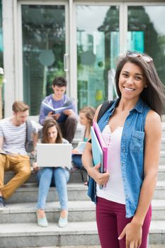 Pretty student smiling at camera outside at the university