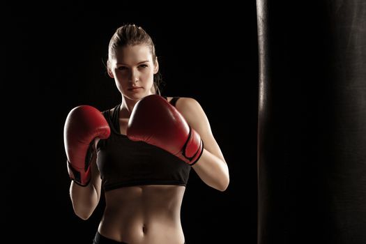 beautiful woman with the red gloves is boxing on black background
