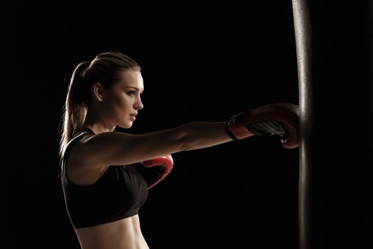 beautiful woman with the red gloves is boxing on black background