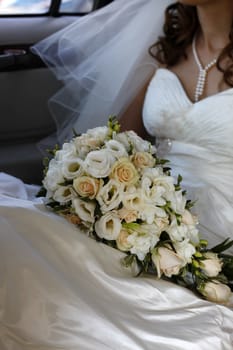 Wedding bouquet from roses on a background of a dress