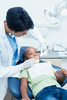 Female dentist examining boys teeth in the dentists chair