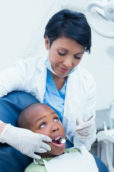Female dentist examining boys teeth in the dentists chair