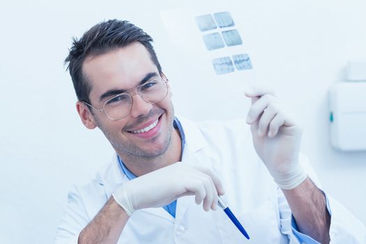 Portrait of smiling male dentist holding at x-ray