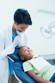 Portrait of smiling female dentist examining boys teeth in the dentists chair