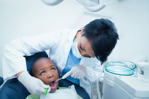 Female dentist examining boys teeth in the dentists chair