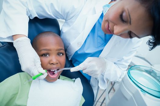 Female dentist examining boys teeth in the dentists chair