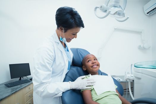 Portrait of smiling female dentist examining boys teeth in the dentists chair