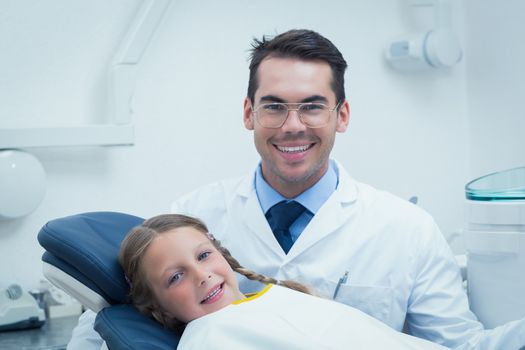 Male dentist examining girls teeth in the dentists chair