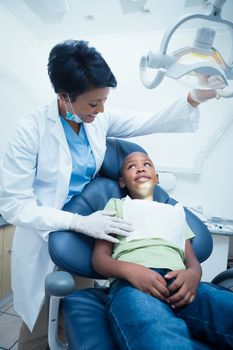 Female dentist examining boys teeth in the dentists chair