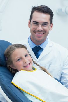 Male dentist examining girls teeth in the dentists chair