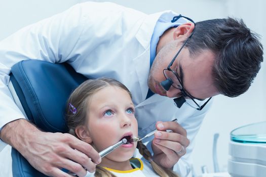 Male dentist examining girls teeth in the dentists chair