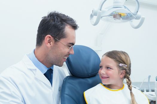 Male dentist examining girls teeth in the dentists chair