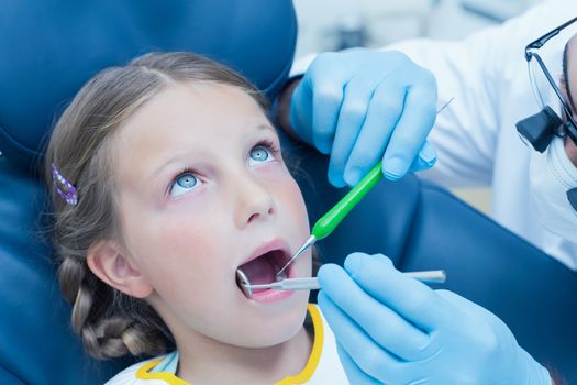 Male dentist examining girls teeth in the dentists chair