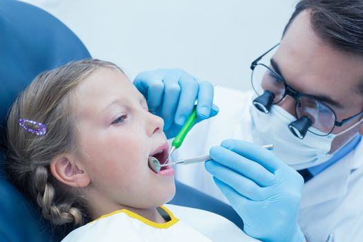 Male dentist examining girls teeth in the dentists chair