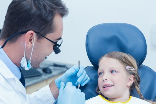 Male dentist examining girls teeth in the dentists chair