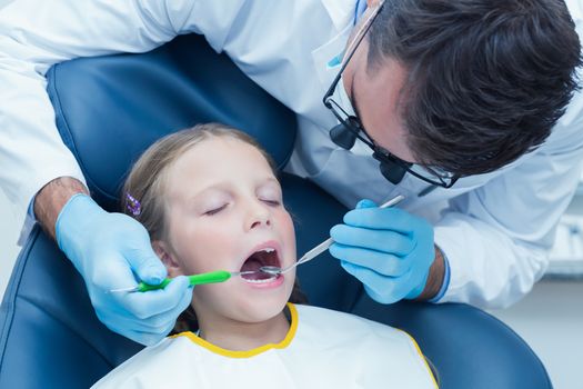 Male dentist examining girls teeth in the dentists chair